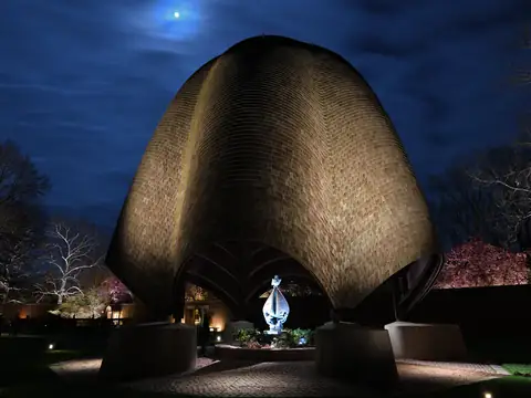 Large domed sculpture grazed with light under a moonlit sky