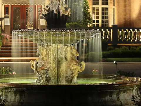 Tiered fountain lit from within in front of a lit facade