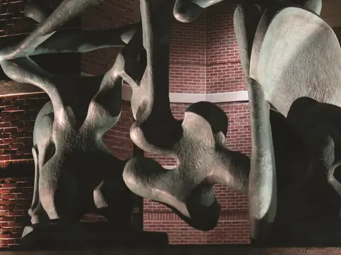 Abstract pale sculpture lit at night against a brick wall, the form modelled by light from two sides