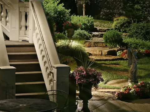 Stone staircase and terraced planting lit at night with an urn and beds picked out below