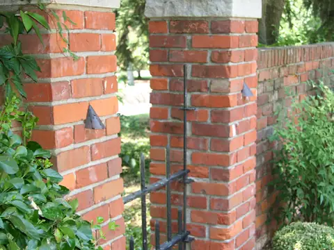 Brick pillar in daylight with a small dark fixture mounted against the mortar and no cable in sight