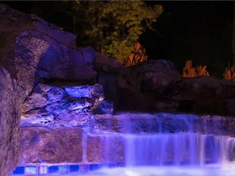 Stone waterfall lit purple by color-changing fixtures