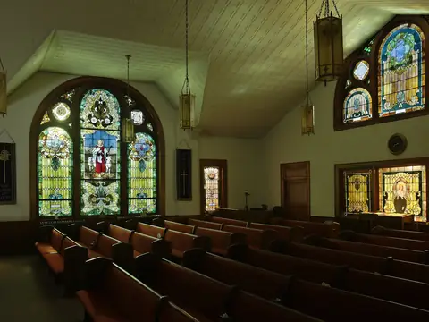 Church interior at night with stained glass windows lit and pews visible down the nave