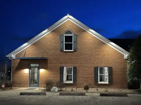 Brick office building at dusk with its gable traced by soffit lighting