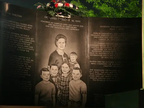 Engraved granite memorial wall lit at night with a family portrait etched into the stone