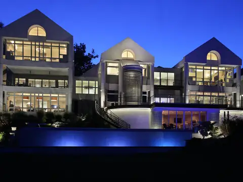 Modern home at blue hour above a lit infinity-edge pool