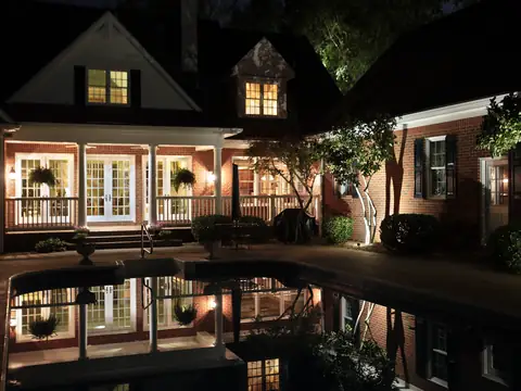 Rear of a lit home reflected in a still pool