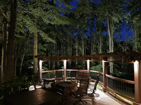 Wood deck with post-cap lights beneath an uplit forest canopy