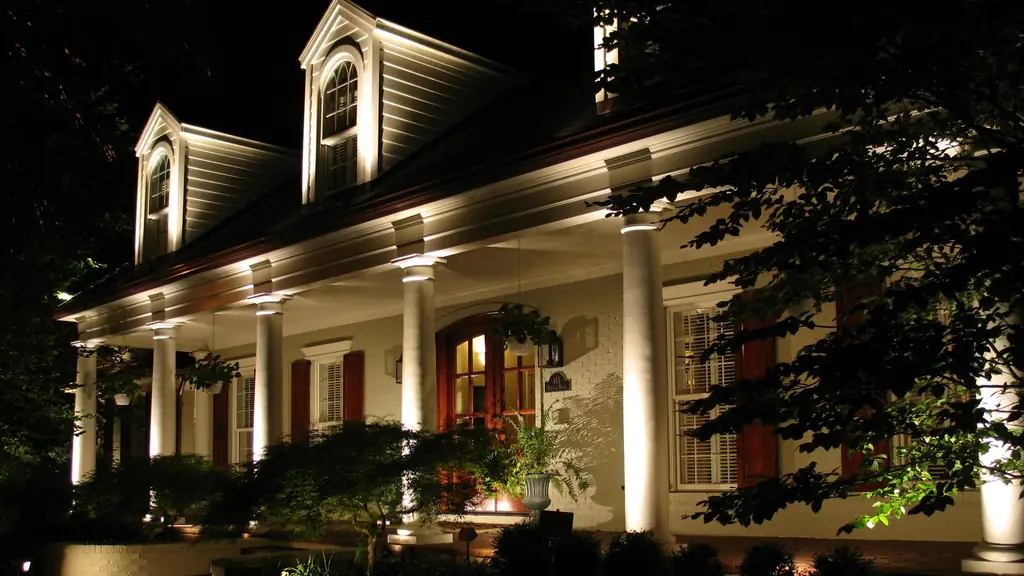 White columned porch at night with downlights recessed into the porch ceiling and warm light across the landscaping