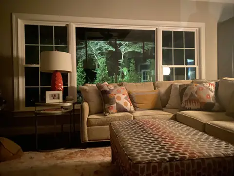 Living room at night with the lit garden filling the picture window