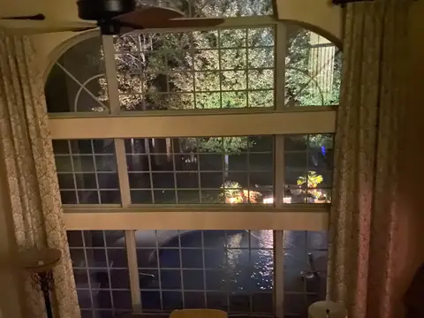 Two-story arched windows at night with the lit pool and yard beyond