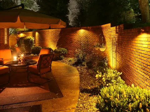 Courtyard seating beside a curved brick wall washed in warm light
