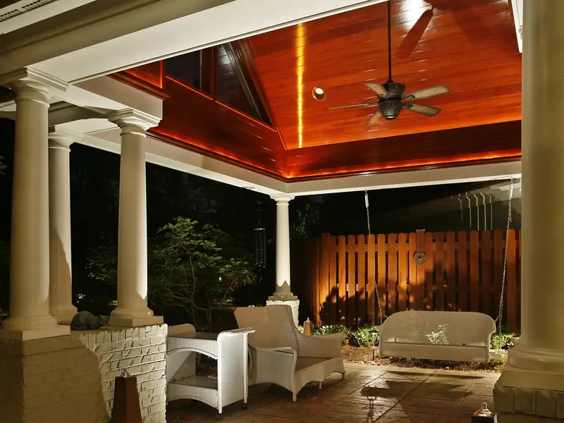 Covered outdoor living area with a timber vaulted ceiling lit from concealed fixtures and a stone fireplace