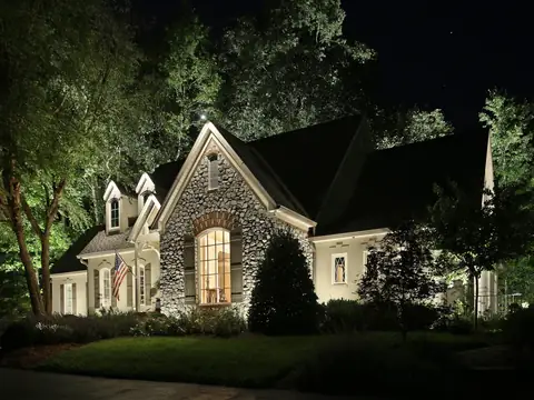 Fieldstone gable washed with light and framed by uplit trees