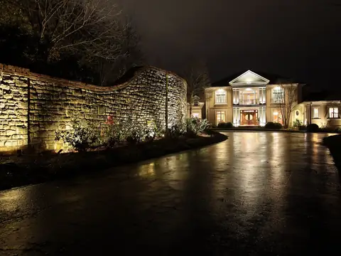 Long stone wall grazed with light along a curving drive