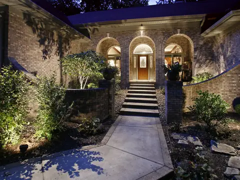 Arched entry with steps and a curved walk lit by path and accent lights