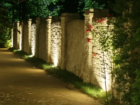 Driveway wall grazed by fixtures hidden in the plantings